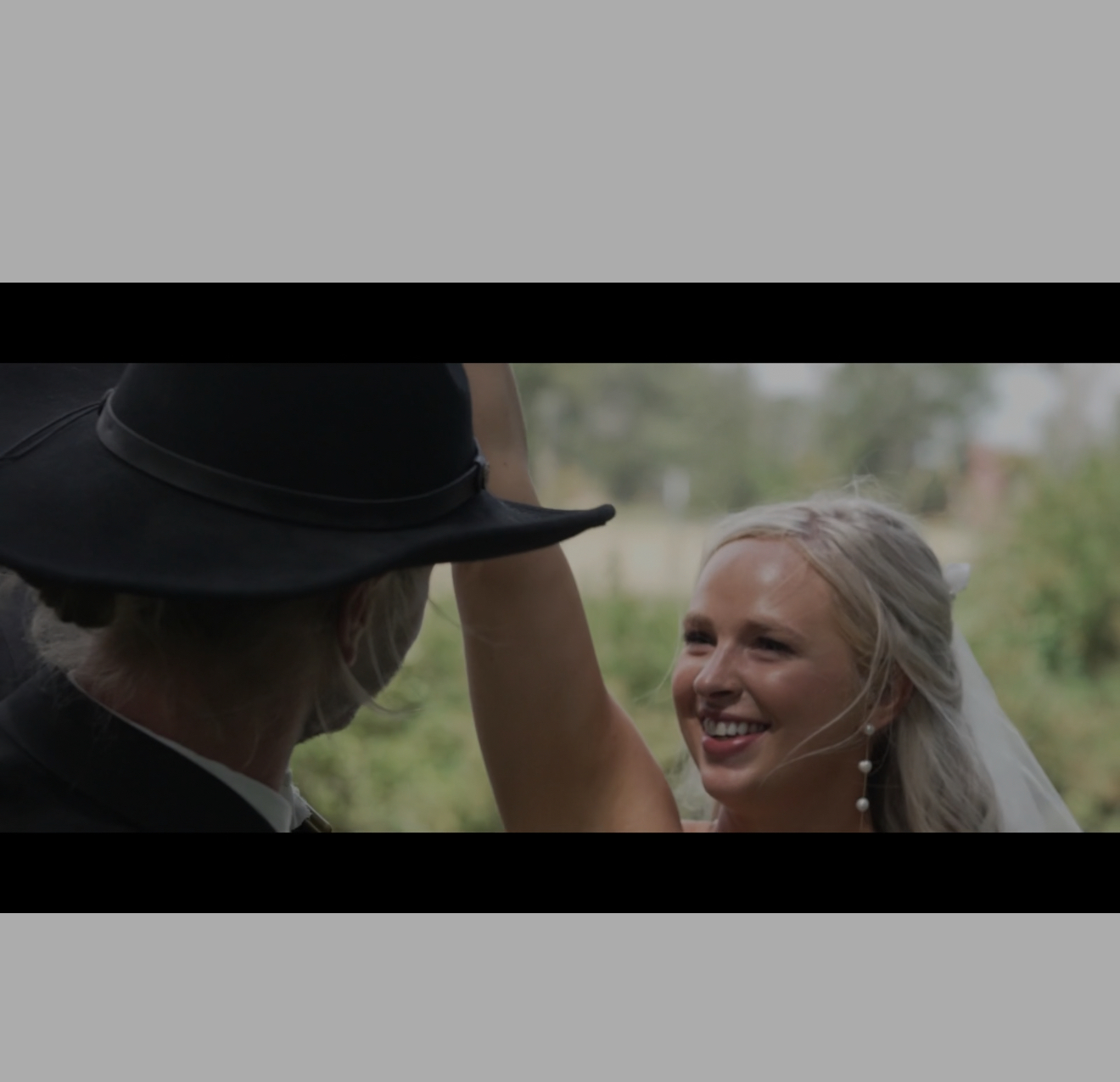 Cinematic wedding video still of a bride smiling at golden hour